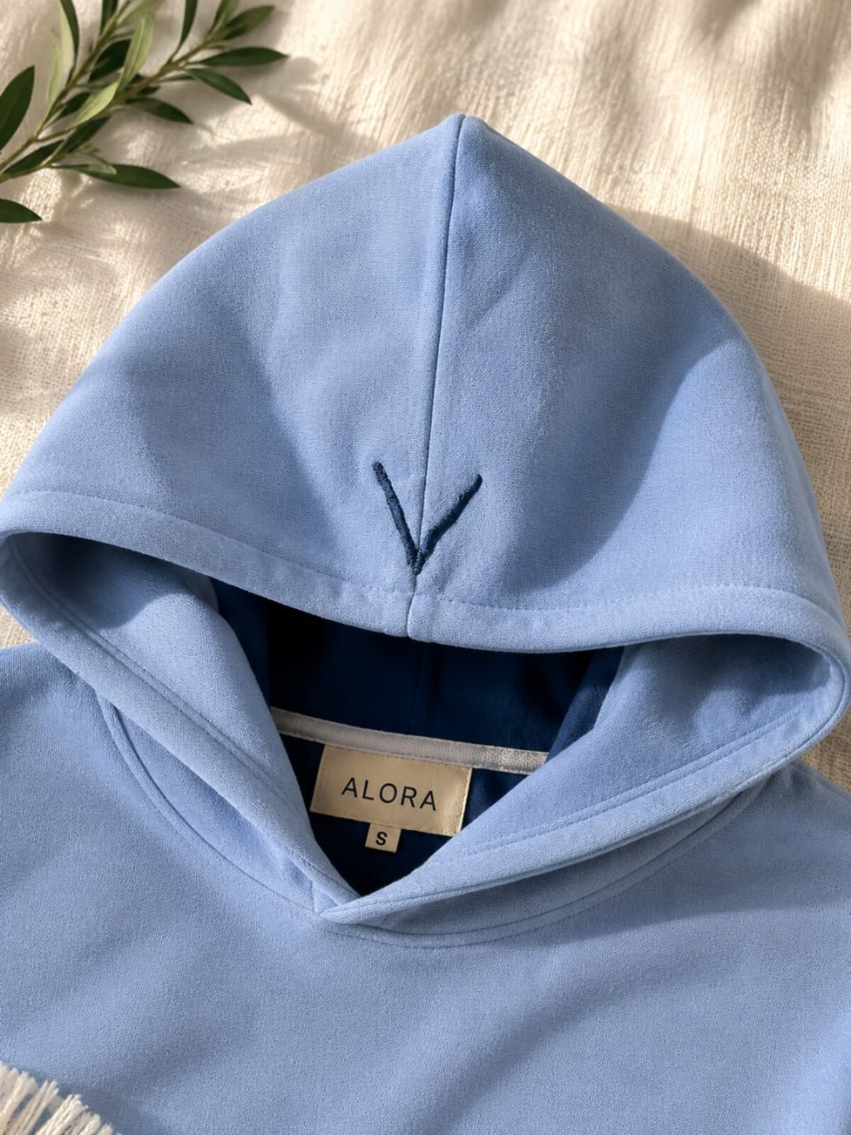 The Alora Hoodie — Sky, hood detail showing the V-stitch and inner silk ALORA size label