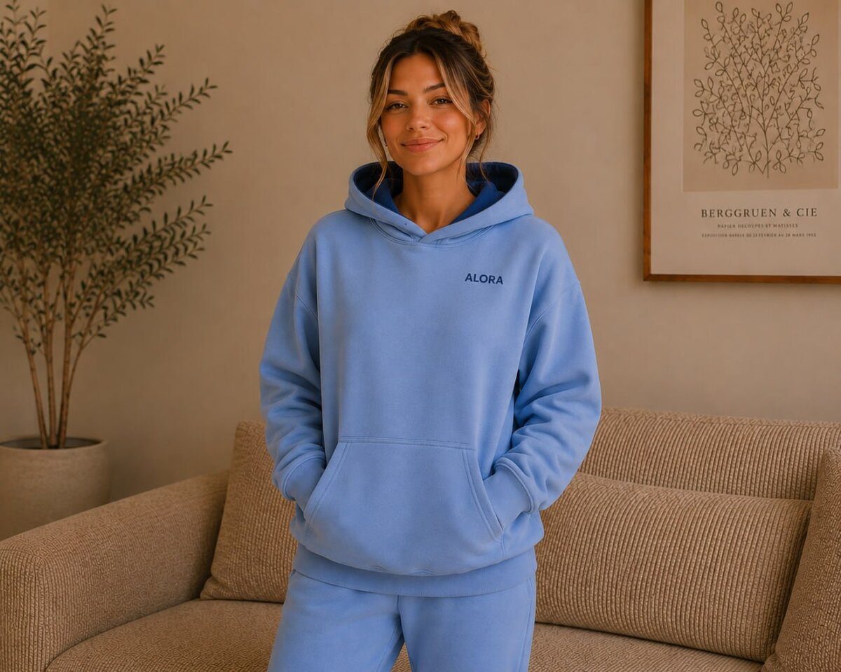 The Alora Hoodie — Sky, front view standing, hood down, chest ALORA puff print